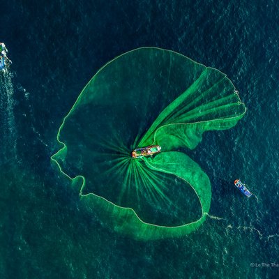 Bức ảnh chụp toàn cảnh trên không cho thấy hoạt động đánh cá cơm truyền thống tại vùng biển Phú Yên với các tàu cá và lưới đánh cá lớn. Hình ảnh mang lại cảm giác bình yên và tôn vinh nét đẹp lao động truyền thống của ngư dân Việt Nam.