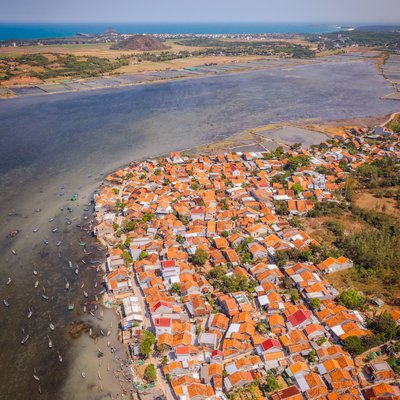 Ảnh chụp toàn cảnh trên không của làng ven biển với mái ngói cam đặc trưng bên đầm Ô Loan. Cảnh vật mang lại cảm giác yên bình và thanh thản dưới ánh sáng tự nhiên rõ ràng.