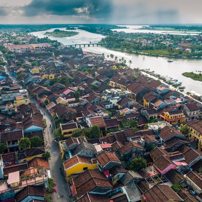 Hình ảnh toàn cảnh trên cao của phố cổ Hội An với kiến trúc truyền thống và dòng sông uốn lượn bên cạnh. Cảnh quan mang lại cảm giác yên bình và hài hoà giữa thiên nhiên và đô thị.