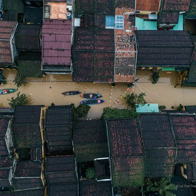Ảnh chụp từ trên cao cho thấy khu phố cổ Hội An bị ngập nước do lũ lụt, với những chiếc thuyền nhỏ di chuyển trên con đường ngập nước giữa các ngôi nhà truyền thống mái ngói. Cảnh tượng mang lại cảm giác yên bình nhưng cũng thể hiện sự thích nghi của người dân với thiên tai.