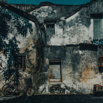Bức ảnh chụp một bức tường cũ kỹ ở phố cổ Hội An với ánh sáng tự nhiên chiếu qua tạo bóng cây trên tường. Hình ảnh gợi lên cảm giác hoài niệm và yên bình về cuộc sống thường nhật trong không gian truyền thống.