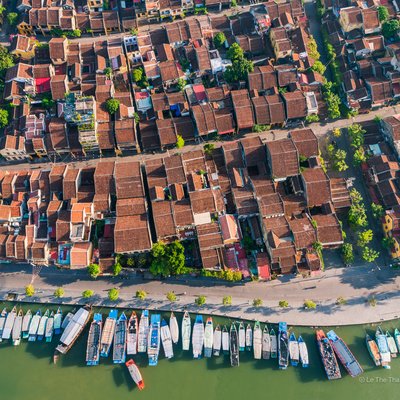 Ảnh chụp từ trên cao cho thấy khu phố cổ Hội An với các mái ngói nâu đặc trưng và dòng sông bên cạnh có nhiều thuyền đậu. Toàn cảnh tạo cảm giác yên bình và tĩnh lặng của một đô thị cổ kính bên bờ sông.