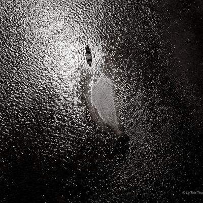 Bức ảnh chụp toàn cảnh trên không của đầm Lập An với ánh sáng tự nhiên chiếu sáng mặt nước tạo ra các gợn sóng phản chiếu. Hình ảnh đen trắng mang lại cảm giác tĩnh lặng và thanh bình cho cảnh quan.