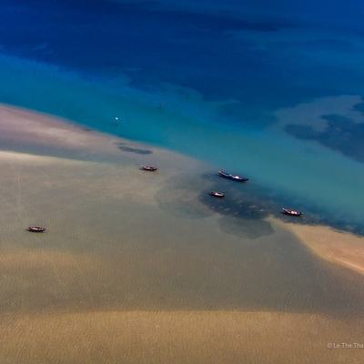 Ảnh chụp hàng không của đầm phá Lập An ở Huế với nước xanh và bãi cát nâu cùng những chiếc thuyền nhỏ. Khung cảnh tạo cảm giác yên bình và tĩnh lặng giữa thiên nhiên miền Trung Việt Nam.