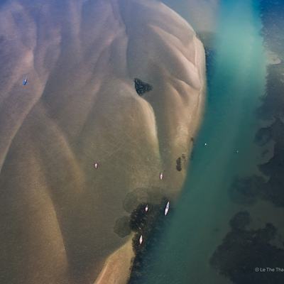 Ảnh chụp từ trên cao cho thấy cảnh sông với bãi cát và những chiếc thuyền nhỏ trên mặt nước xanh. Toàn cảnh mang lại cảm giác yên bình và tĩnh lặng của vùng đất miền Trung Việt Nam.