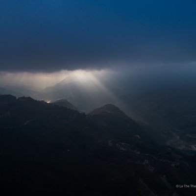 Bức ảnh chụp cảnh núi non và thung lũng ở Sa Pa vào buổi sáng với ánh sáng mặt trời xuyên qua lớp mây và sương mù. Cảnh vật tạo cảm giác yên bình và huyền ảo, mang đến vẻ đẹp tự nhiên tĩnh lặng của vùng núi Tây Bắc Việt Nam.