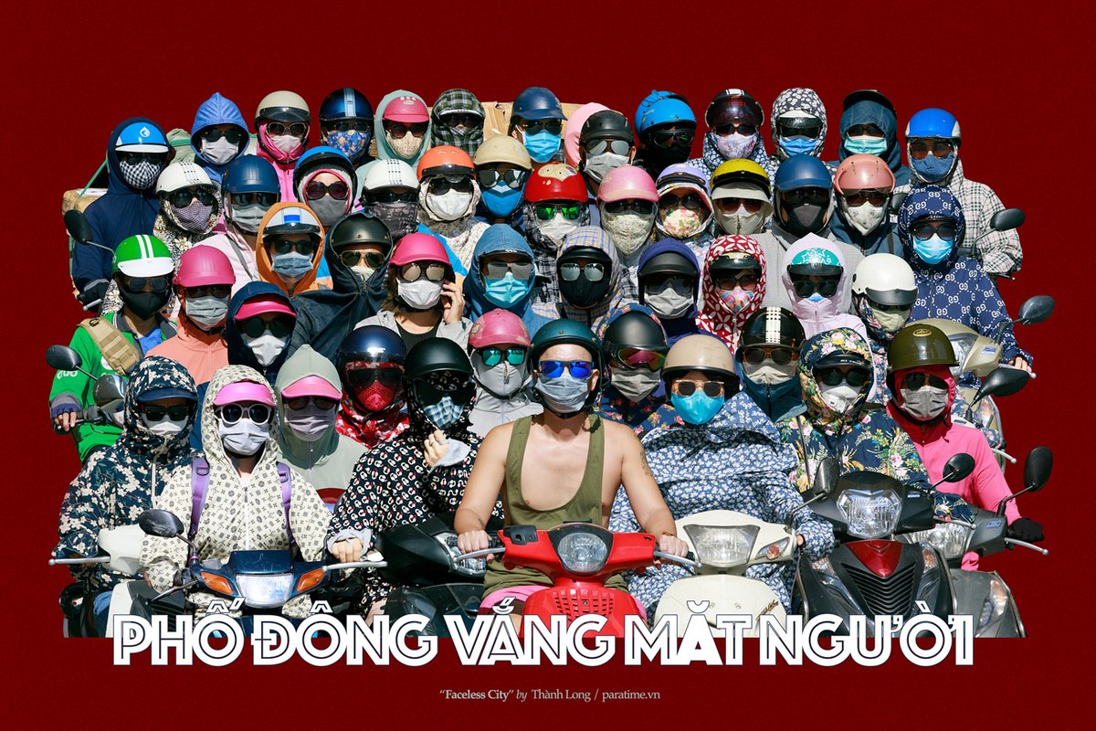 Bức ảnh chụp một nhóm đông người đi xe máy trong thành phố, tất cả đều đeo khẩu trang và đội mũ bảo hiểm với trang phục che kín mặt. Hình ảnh tạo cảm giác sôi động và đầy màu sắc nhưng cũng có phần bí ẩn do không thấy rõ khuôn mặt.