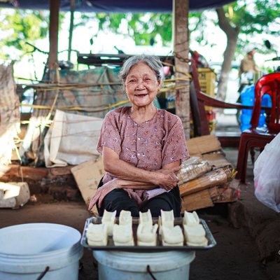 Bức ảnh chụp một bà lão đang bán đậu tại chợ ngoài trời ở thôn Dai Tu. Hình ảnh mang lại cảm giác ấm áp và chân thực về cuộc sống thường nhật của người dân địa phương.