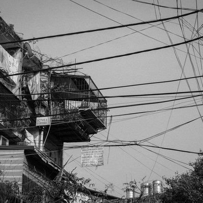 Bức ảnh chụp một phần của nhà tập thể với các chuồng cọp được cơi nới và nhiều dây điện chằng chịt phía trước. Hình ảnh gợi lên cảm giác hoài niệm về cuộc sống đô thị truyền thống ở Hà Nội.