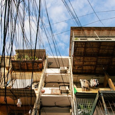 Bức ảnh chụp một toà nhà tập thể cũ với các ban công được bảo vệ bằng lưới sắt, dây điện chằng chịt phía trước. Hình ảnh gợi lên cảm giác hoài niệm về cuộc sống đô thị truyền thống tại Hà Nội.