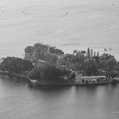 Bức ảnh chụp một góc Hồ Tây ở Hà Nội với một đảo nhỏ có nhiều cây xanh và công trình kiến trúc. Khung cảnh tạo cảm giác yên bình và tĩnh lặng giữa không gian rộng lớn của mặt nước.