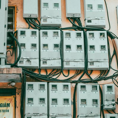 Bức ảnh chụp các đồng hồ điện gắn trên một bức tường cũ với nhiều dây điện nối liền. Hình ảnh tạo cảm giác bình dị và mang nét đặc trưng của đô thị Hà Nội.