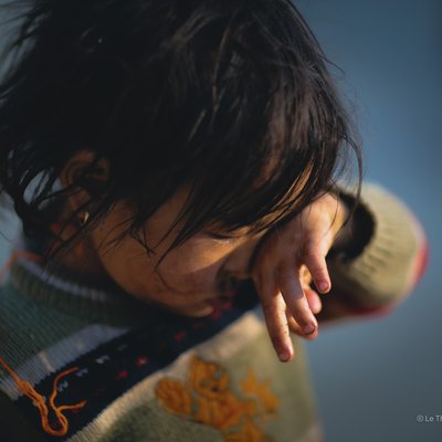 Bức ảnh chụp một em bé đang dụi mắt, mặc áo len có hoạ tiết. Hình ảnh mang lại cảm giác nhẹ nhàng, sâu lắng và có chút buồn man mác.