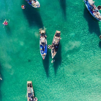 Hình ảnh chợ cá Tam Tiến tại Quảng Nam với các tàu cá neo đậu trên mặt nước biển trong xanh. Cảnh tượng mang lại cảm giác yên bình và truyền thống của cuộc sống ven biển miền Trung Việt Nam.