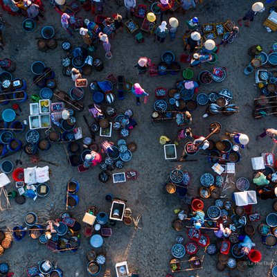 Ảnh chụp từ trên cao cho thấy chợ cá Tam Tiến nhộn nhịp với nhiều người bán và mua cá trên bãi biển. Không khí sôi động và đầy màu sắc tạo cảm giác sống động và truyền thống của miền Trung Việt Nam.