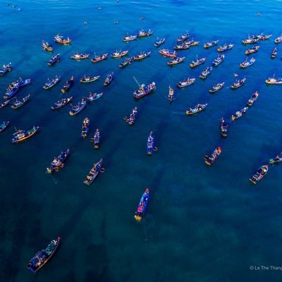 Ảnh chụp từ trên cao cho thấy nhiều tàu cá đang hoạt động trên biển tại chợ cá Tam Tiến, Quảng Nam. Cảnh tượng tạo cảm giác nhộn nhịp và sống động của một khu chợ truyền thống ven biển.