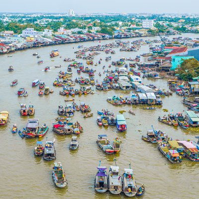 Hình ảnh chợ nổi Cái Răng trên sông với nhiều thuyền buôn bán và nhà ven sông ở Cần Thơ. Cảnh quan sôi động và đầy màu sắc thể hiện nhịp sống đặc trưng của vùng đồng bằng sông Cửu Long.