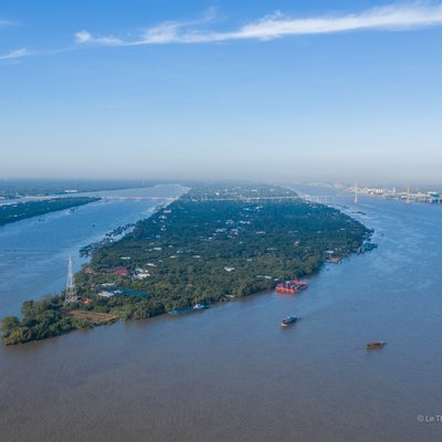 Ảnh chụp toàn cảnh sông Tiền Giang tại Mỹ Tho với dòng sông rộng lớn, cây xanh và các thuyền nhỏ trên mặt nước. Cảnh vật tạo cảm giác yên bình và tĩnh lặng dưới bầu trời trong xanh.