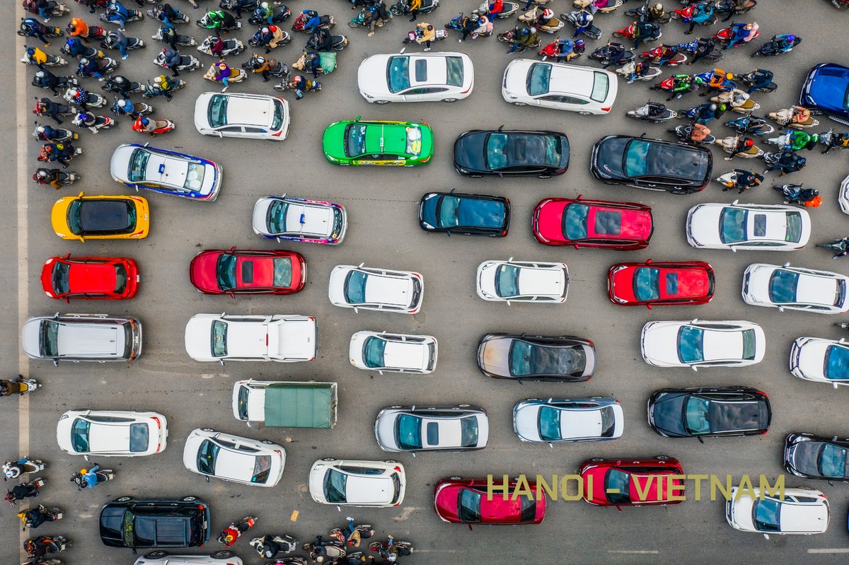Ảnh chụp từ trên cao cho thấy cảnh giao thông đông đúc với nhiều ô tô và xe máy trên đường phố Hà Nội. Hình ảnh thể hiện sự sôi động và nhộn nhịp đặc trưng của cuộc sống đô thị tại Việt Nam.