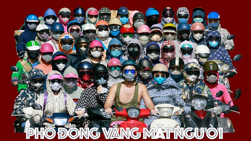 Bức ảnh chụp một nhóm đông người đi xe máy trong thành phố, tất cả đều đeo khẩu trang và đội mũ bảo hiểm với trang phục che kín mặt. Hình ảnh tạo cảm giác sôi động và đầy màu sắc nhưng cũng có phần bí ẩn do không thấy rõ khuôn mặt.