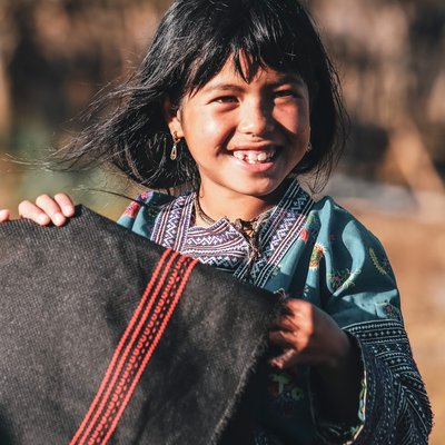 Bé gái dân tộc ở Mộc Châu mặc trang phục truyền thống, cười tươi trong ánh nắng tự nhiên