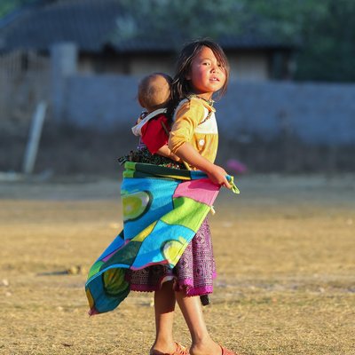 Bức ảnh chụp hai chị em ở vùng nông thôn Mộc Châu, Sơn La, với ánh sáng tự nhiên chiếu lên khuôn mặt và trang phục truyền thống. Hình ảnh mang lại cảm giác ấm áp và chân thực về cuộc sống gia đình vùng cao.