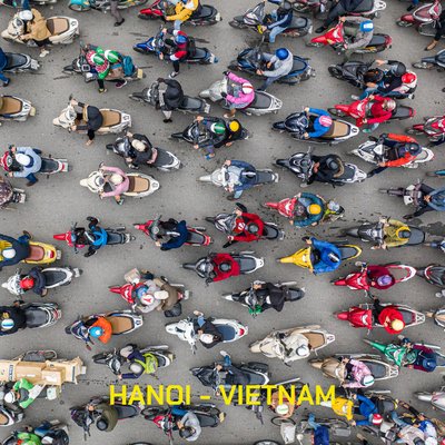 Ảnh chụp từ trên cao cho thấy cảnh đông đúc của người đi xe máy trên đường phố Hà Nội vào buổi sáng với ánh sáng tự nhiên. Bức ảnh mang lại cảm giác sống động và nhộn nhịp của cuộc sống đô thị hàng ngày.
