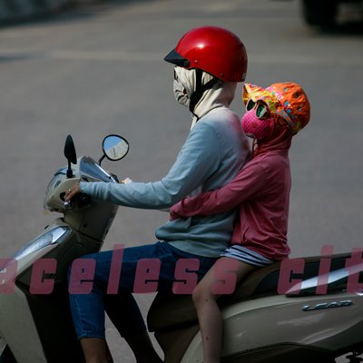 Bức ảnh chụp hai người trên xe máy, đều mặc đồ bảo vệ và đeo khẩu trang, mũ bảo hiểm để tránh ô nhiễm và bụi bẩn. Cảnh tượng tạo cảm giác bình yên nhưng cũng gợi lên sự cần thiết của việc bảo vệ sức khoẻ trong môi trường đô thị.