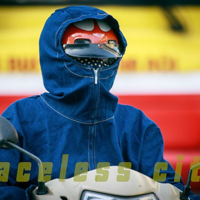 Hình ảnh một người mặc áo chống nắng và mũ bảo hiểm đi xe máy trên đường phố thành phố. Bức ảnh tạo cảm giác cô lập và nhấn mạnh sự vắng mặt rõ ràng của khuôn mặt người trong cảnh đô thị.