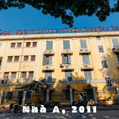 Bức ảnh chụp một toà nhà đại học tại Hà Nội với người đi xe đạp trên đường phố phía trước. Cảnh vật tạo cảm giác yên bình và sinh động của cuộc sống đô thị buổi sáng.